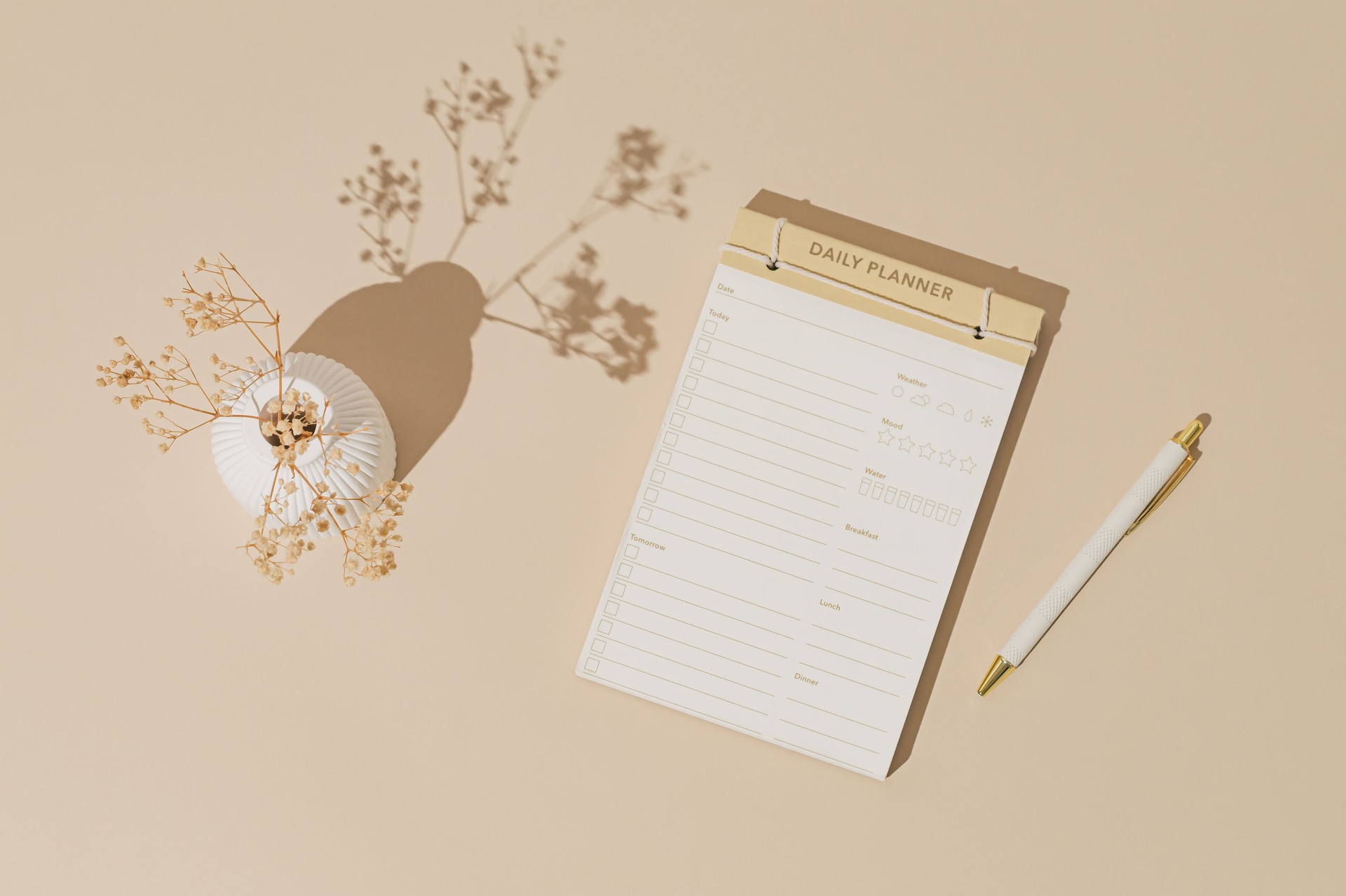 Trendy layout made with daily planner, pen and white vase with dry flowers on pastel cream background. Minimal creative concept. Flat lay, top of view.