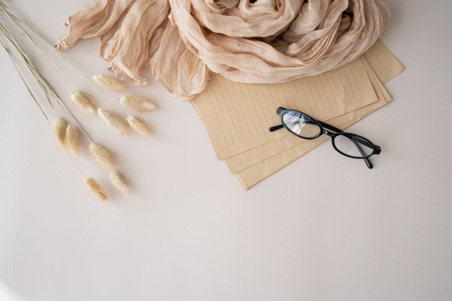 Desk workspace with notes, glasses and scarf on a beige background. Flat lay, top view, blog, website, social media concept. Trendy feminine accessories arrangement.
